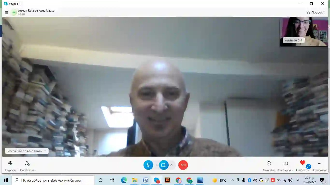 Josean on a Skype Greek lesson, bookshelves behind