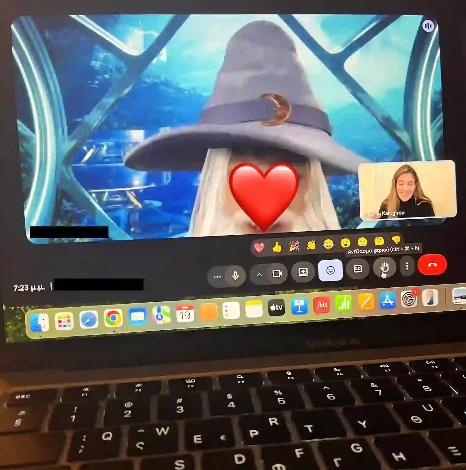 A young student on a video Greek lesson wearing a fun wizard-hat filter, sending a heart to the teacher